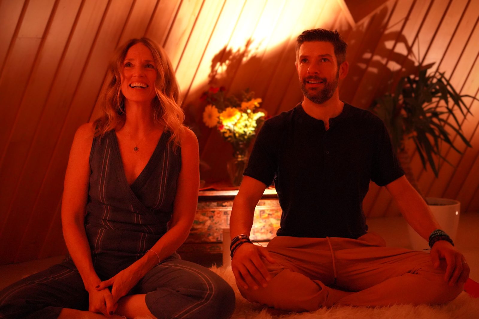 Sarah and Travis seated together in a candlelit workshop space